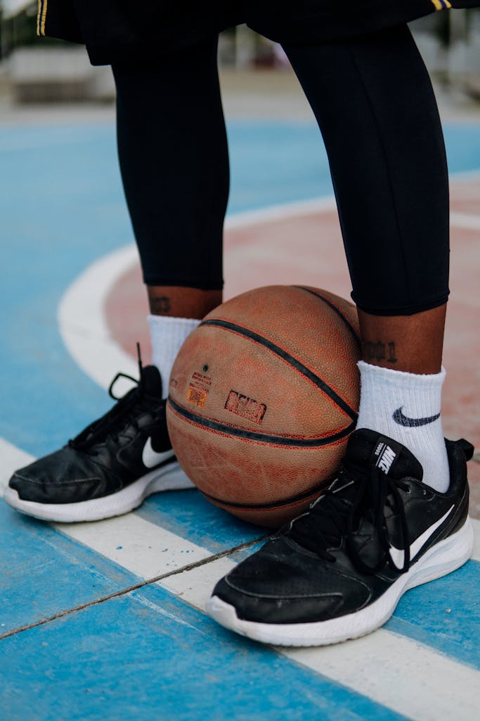 A focused shot of a basketball player's sneakers and ball on a colorful outdoor court.
