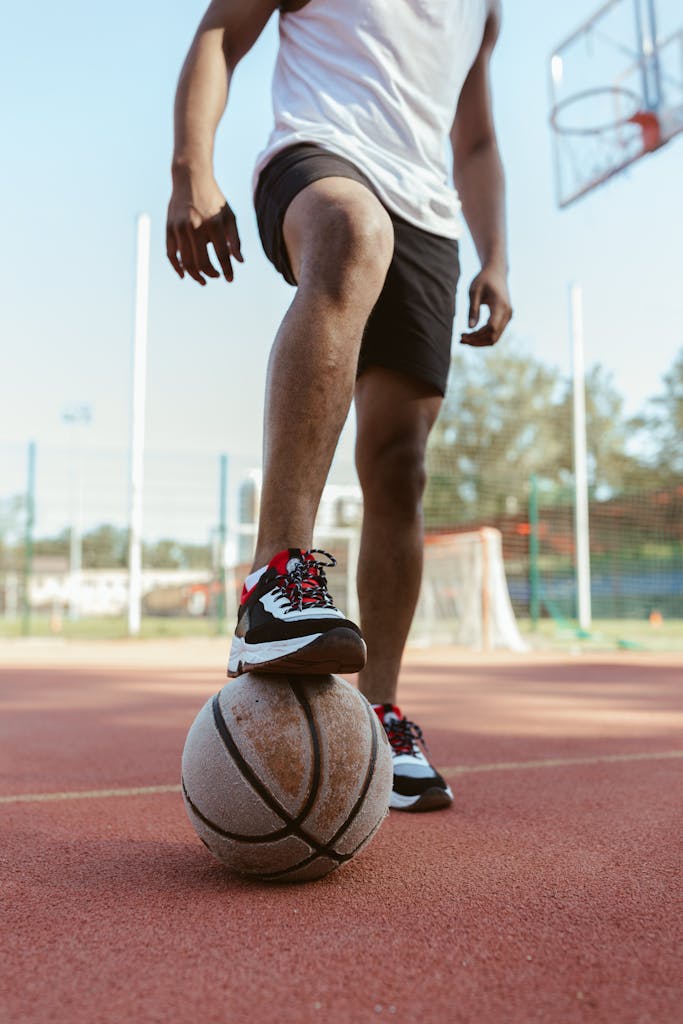 A player skillfully dribbles a basketball on an outdoor court, emphasizing their athletic shoes and stance.